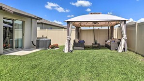 A covered patio area with outdoor furniture, a grill, and a water feature.