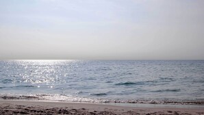 Een strand met rustig water en een heldere lucht.