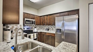 A modern kitchen with stainless steel appliances, granite countertops, and wooden cabinets.