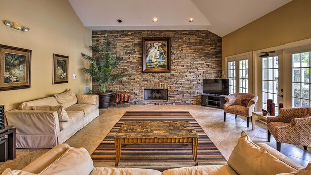 A living room with a stone fireplace, a sofa, armchairs, and a television.