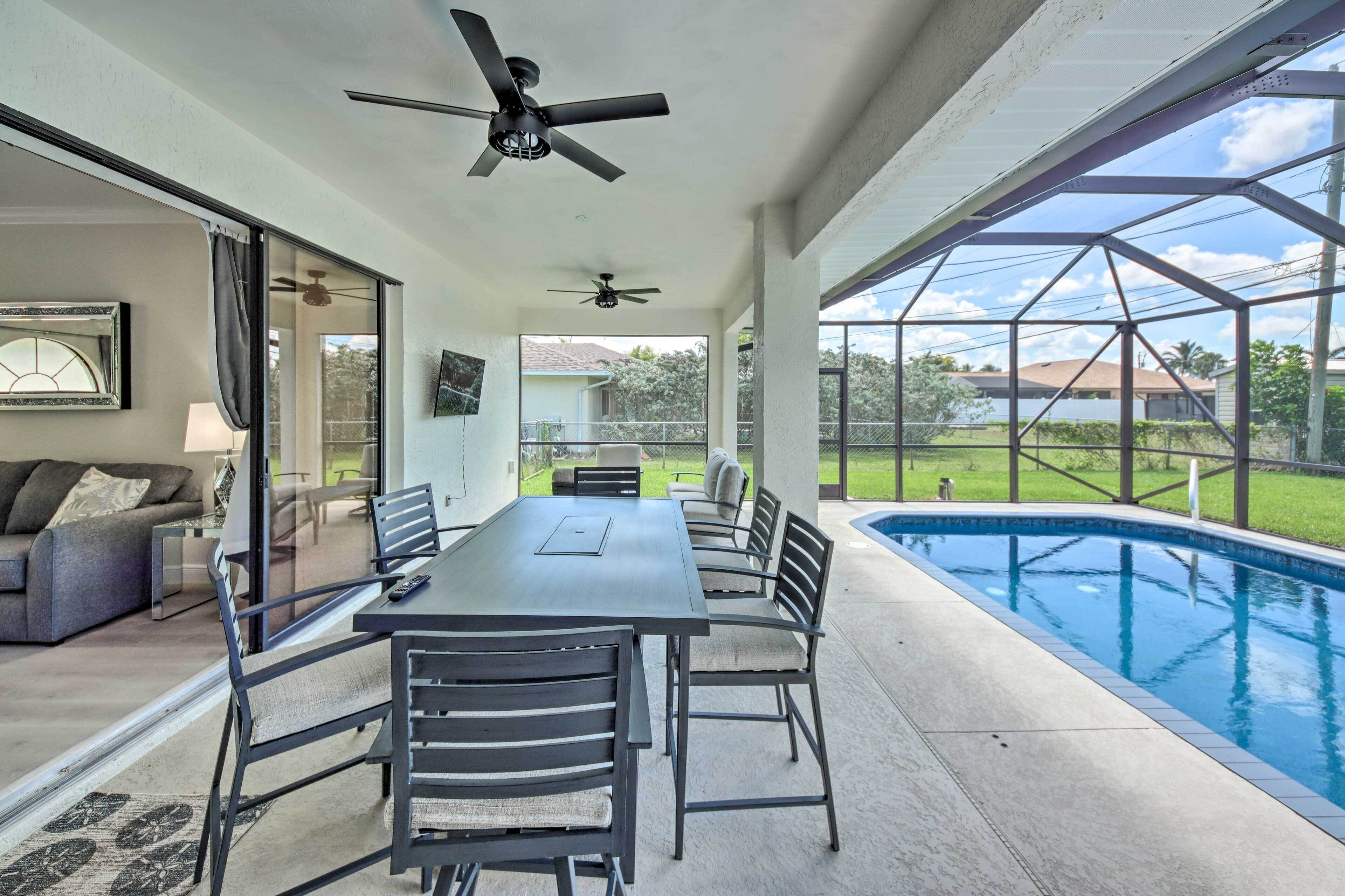 A covered patio with a pool, a dining table with chairs, and a ceiling fan.