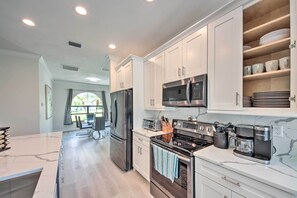 A modern kitchen with white cabinets, stainless steel appliances, and a marble countertop. - Lanai + Pool: Dog-friendly Home in Cape Coral! (Cape Coral)