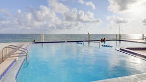 A swimming pool with a view of the sea, a metal ladder, and a tiled edge. - Dolphin & Manatee Viewing From 15th Floor & Pool! (Clearwater Beach)