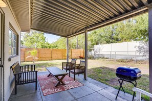 A covered patio area with a grill, seating, and a view of the backyard. - Modern Lakeland Vacation Rental: Patio & BBQ Grill (Lakeland)