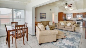 A spacious living area with a dining table and chairs, a sofa, and a kitchen in the background. - Ormond Beach Vacation Rental - Walk to Ocean! (Ormond Beach)