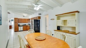 A spacious kitchen with white cabinetry, a wooden dining table, and a ceiling fan. - Ormond Beach Vacation Rental - Walk to Ocean! (Ormond Beach)