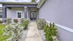 A modern house with a grey exterior, a front door, and a pathway leading to the entrance. - Palm Bay Home w/ Patio & Yard - 12 Mi to Beach! (Palm Bay)