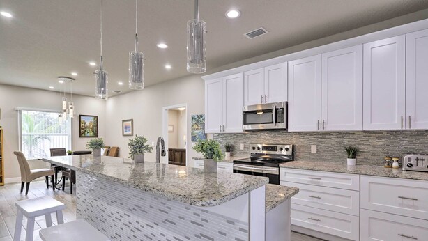 A modern kitchen with white cabinets, granite countertops, and stainless steel appliances. - Palm Bay Home w/ Patio & Yard - 12 Mi to Beach! (Palm Bay)