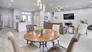 A spacious living area with a round wooden dining table, leather chairs, a gray sofa, and a ceiling fan. - Palm Bay Home w/ Patio & Yard - 12 Mi to Beach! (Palm Bay)