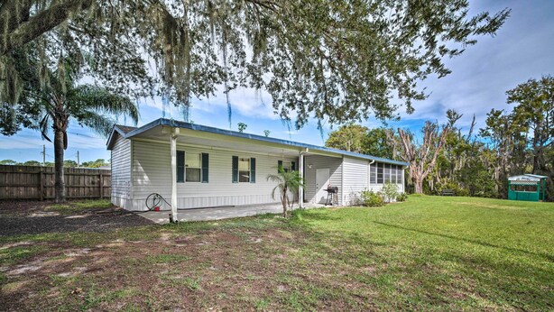 A single-story house with a covered porch, a small yard, and a wooden fence in the background. - Peaceful Canal-front Retreat w/ Boathouse! (Leesburg)