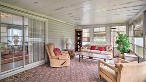 A cozy living room with a large window, a sofa, a chair, and a coffee table. - Peaceful Canal-front Retreat w/ Boathouse! (Leesburg)