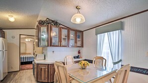 A compact kitchen with wooden cabinets, a dining table with chairs, and a ceiling light fixture. - Peaceful Canal-front Retreat w/ Boathouse! (Leesburg)