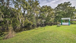 A grassy area with a small pond, trees, and a gazebo with a bench. - Peaceful Canal-front Retreat w/ Boathouse! (Leesburg)