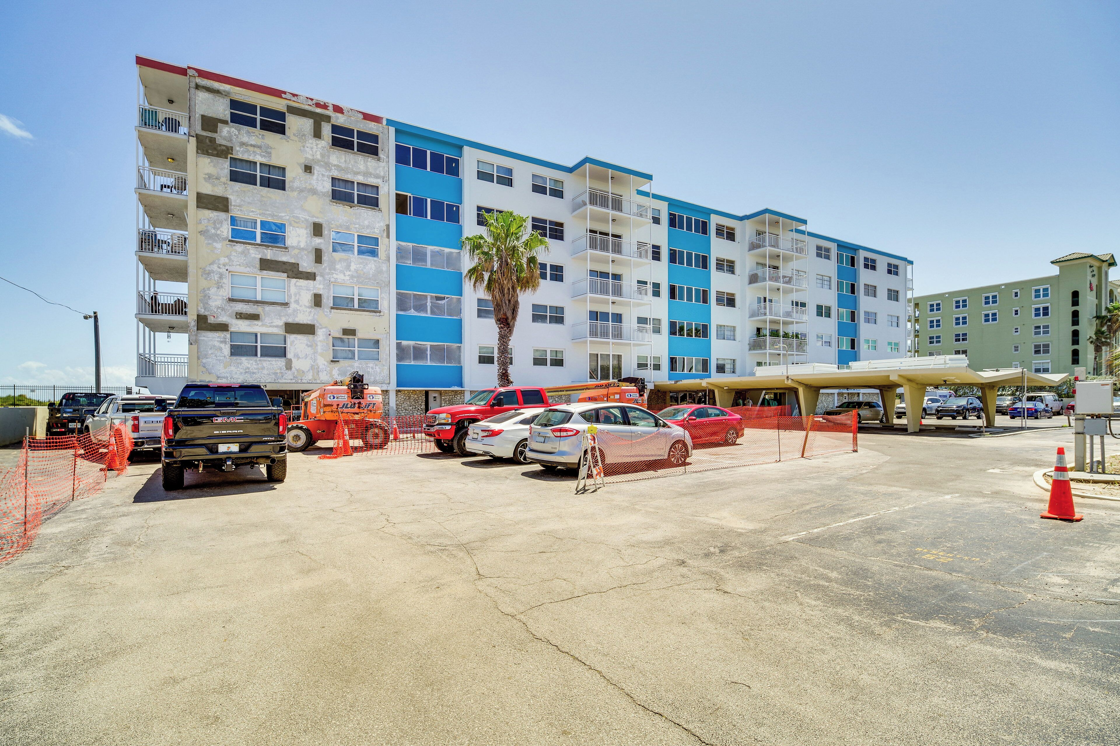 A multi-story building with a parking lot in front.