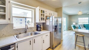 Eine moderne Küche mit weißen Schränken, einem Edelstahl-Kühlschrank und einem großen Fenster.
