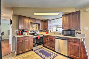 A modern kitchen with wooden cabinets, stainless steel appliances, and a granite countertop. - Family Home w/ Lanai & Yard in Port Richey! (Port Richey)