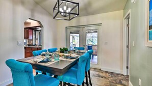 A dining area with a dark wooden table, blue upholstered chairs, and a modern chandelier. - Port Charlotte Retreat w/ Heated Pool & Spa! (Port Charlotte)