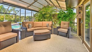 A covered outdoor seating area with wicker furniture and a view of a swimming pool. - Port Charlotte Retreat w/ Heated Pool & Spa! (Port Charlotte)