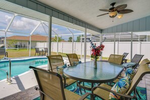 A covered patio with a pool, outdoor seating, and a ceiling fan.