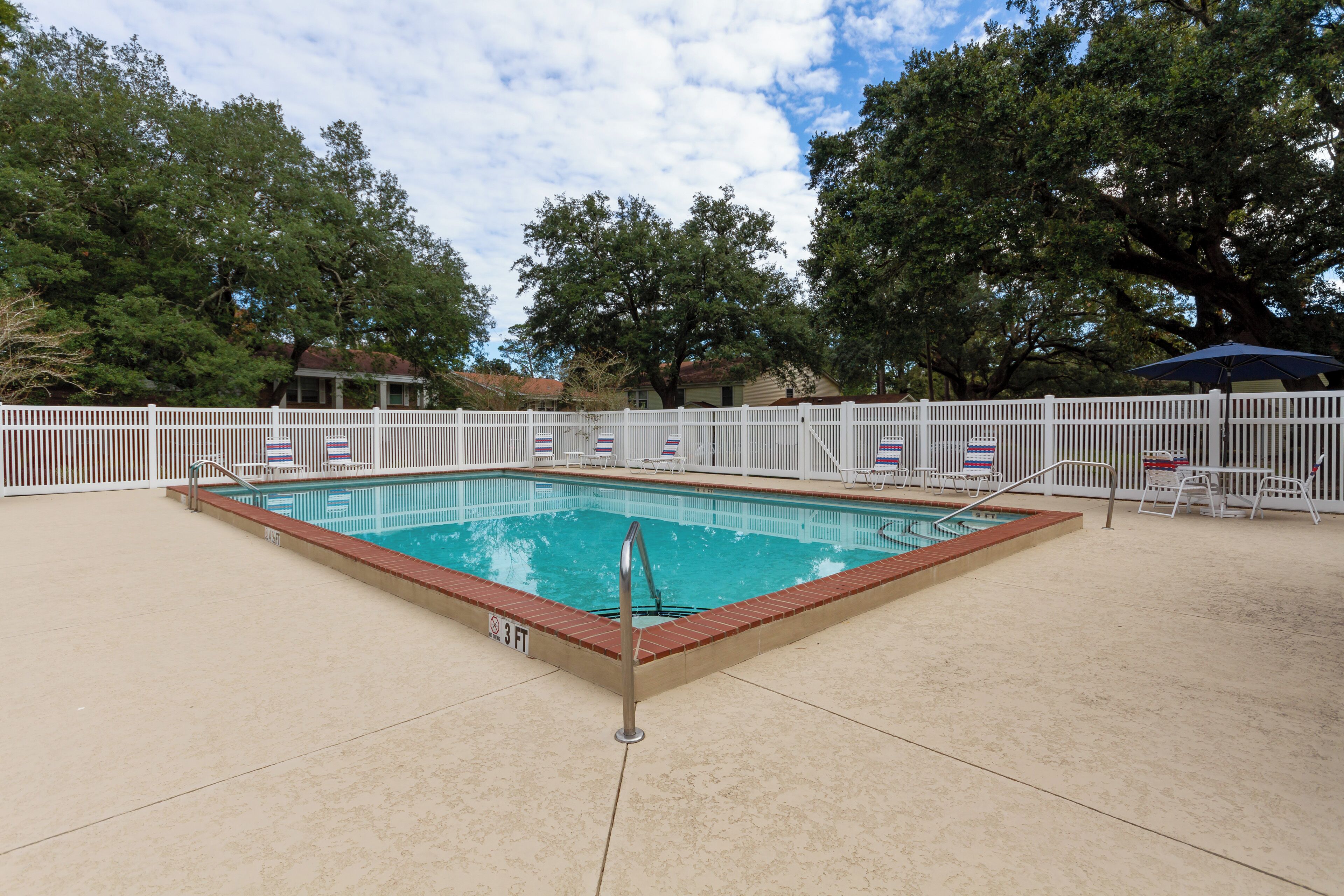 A rectangular pool with a white fence and a lifeguard stand.
