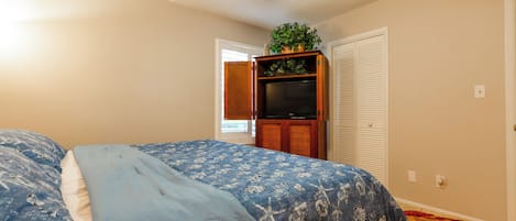 Ein Schlafzimmer mit Bett, Deckenventilator, Fernseher und Kleiderschrank.