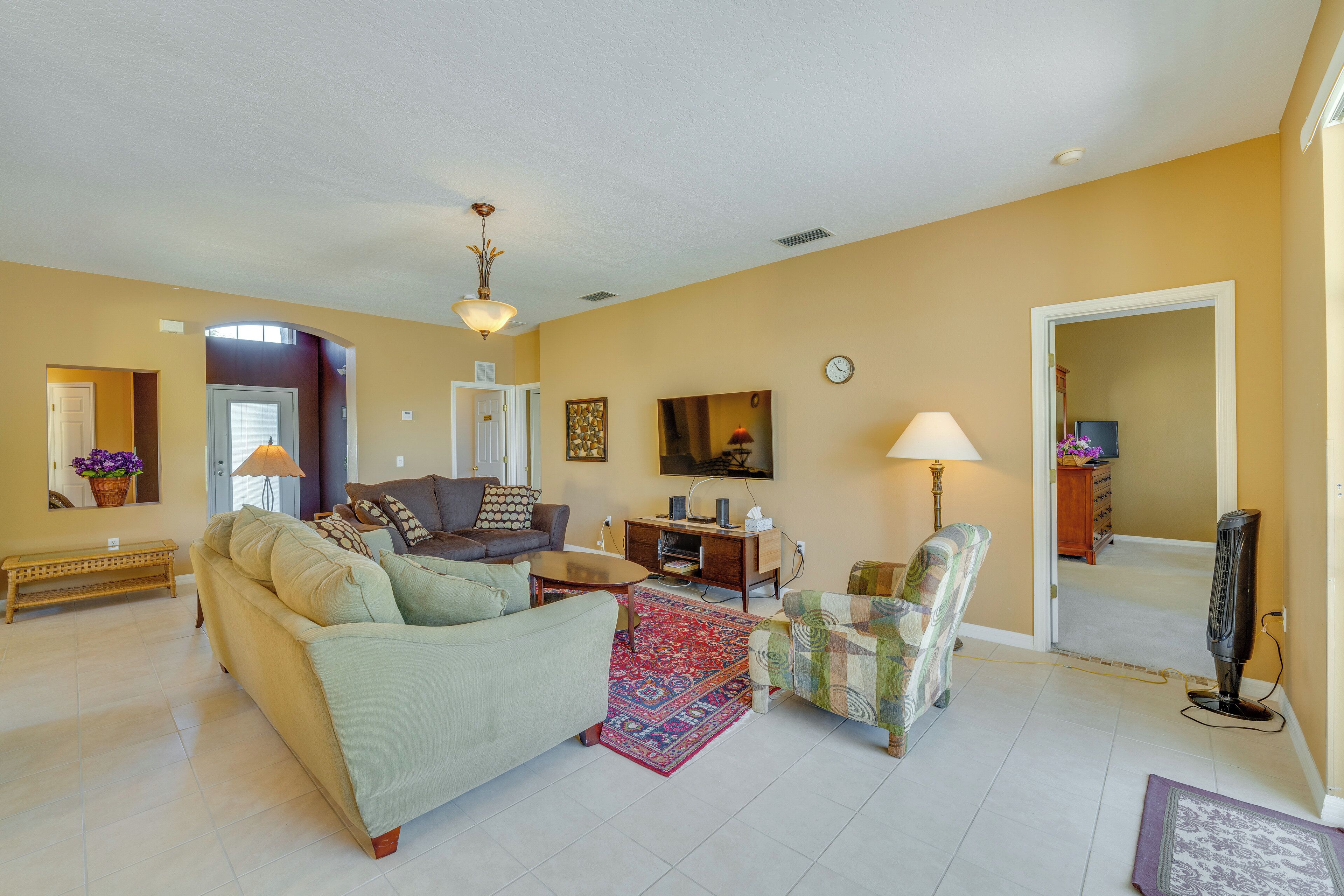 A spacious living room with a sofa, armchair, and a television.