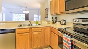 A modern kitchen with wooden cabinets, a stainless steel dishwasher, a microwave, and a stove.