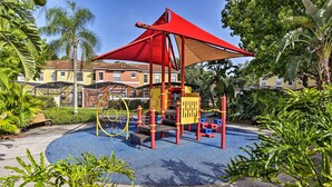 A playground with a red canopy and climbing structures.