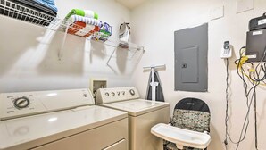 A laundry room with a washing machine, dryer, and ironing station.