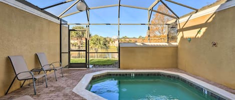A covered outdoor swimming pool with lounge chairs and a clear view of the surrounding area.