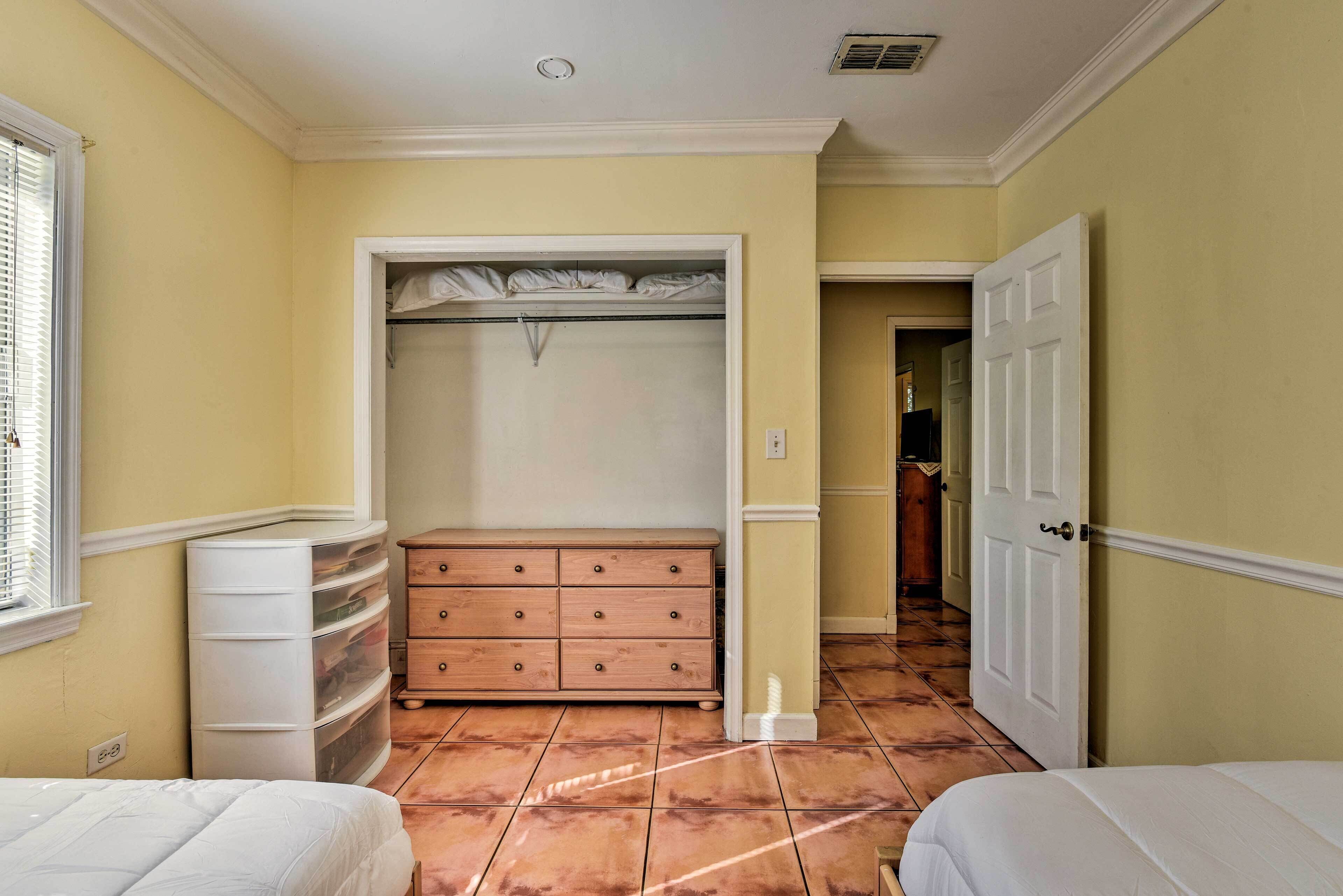 A bedroom with a bed, a dresser, a closet, and a door leading to another room.