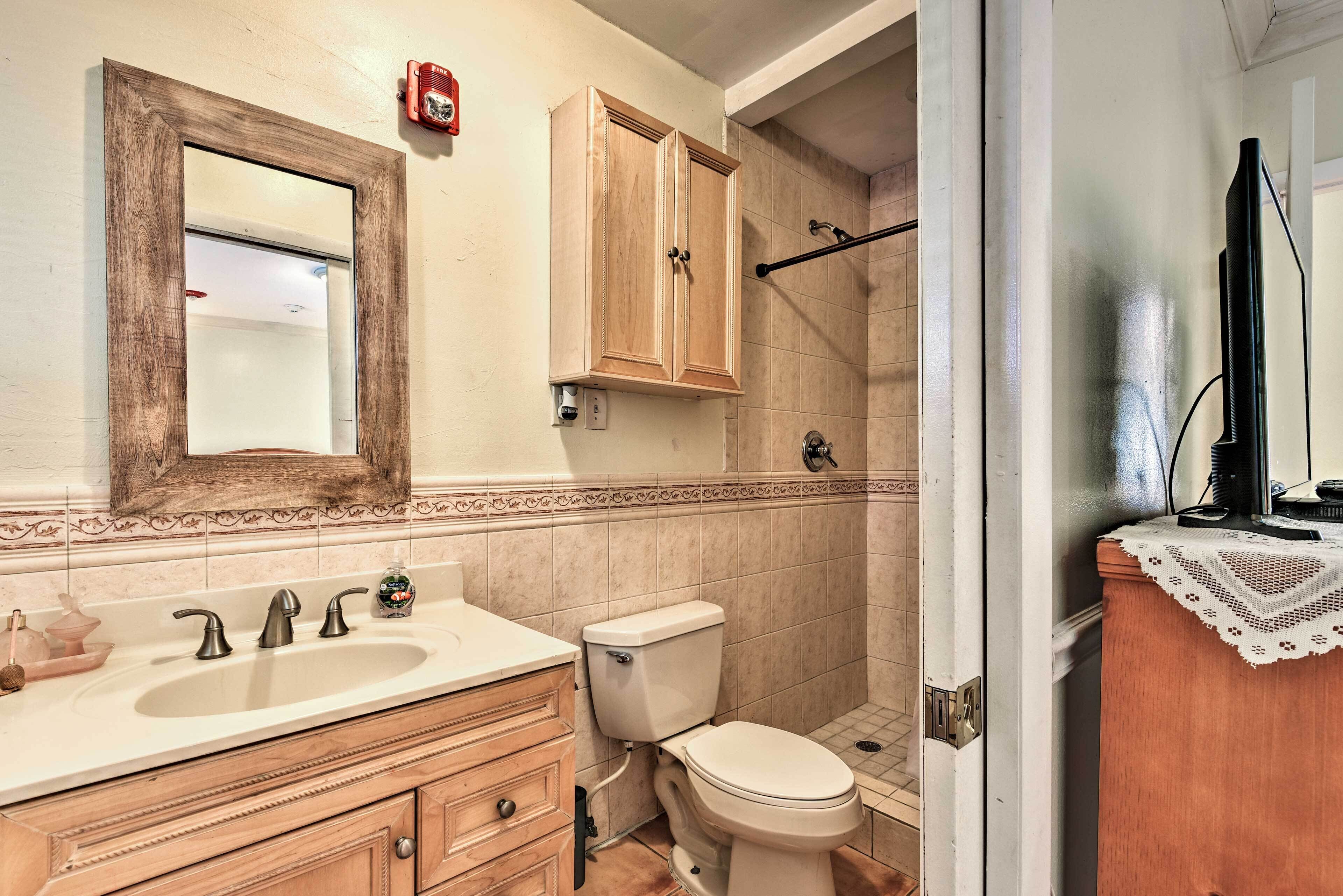 A bathroom with a sink, vanity, toilet, and shower.