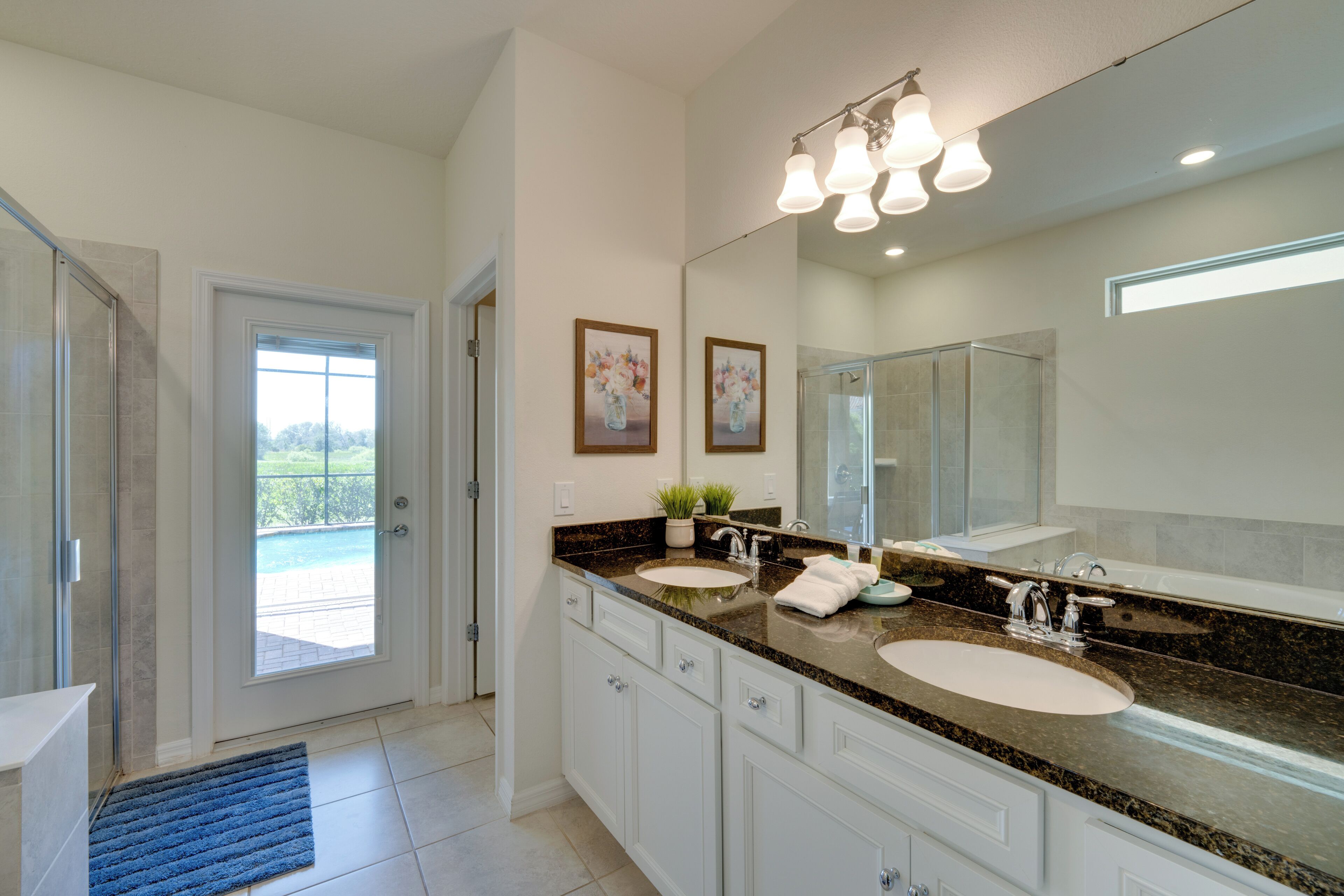 A modern bathroom with two sinks, a large mirror, and a shower area.