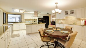 A modern kitchen with white cabinets, a dining table with chairs, and a large window. - Relaxing Tampa Abode w/ Screened Lanai & Pool (Tampa)