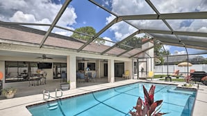 A covered outdoor swimming pool with a patio area, including tables and chairs, and a view of the surrounding buildings. - Relaxing Tampa Abode w/ Screened Lanai & Pool (Tampa)