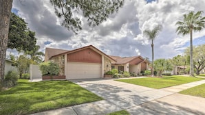 A residential neighborhood with houses featuring stone and stucco exteriors, well-maintained lawns, and a clear sky. - Relaxing Tampa Abode w/ Screened Lanai & Pool (Tampa)