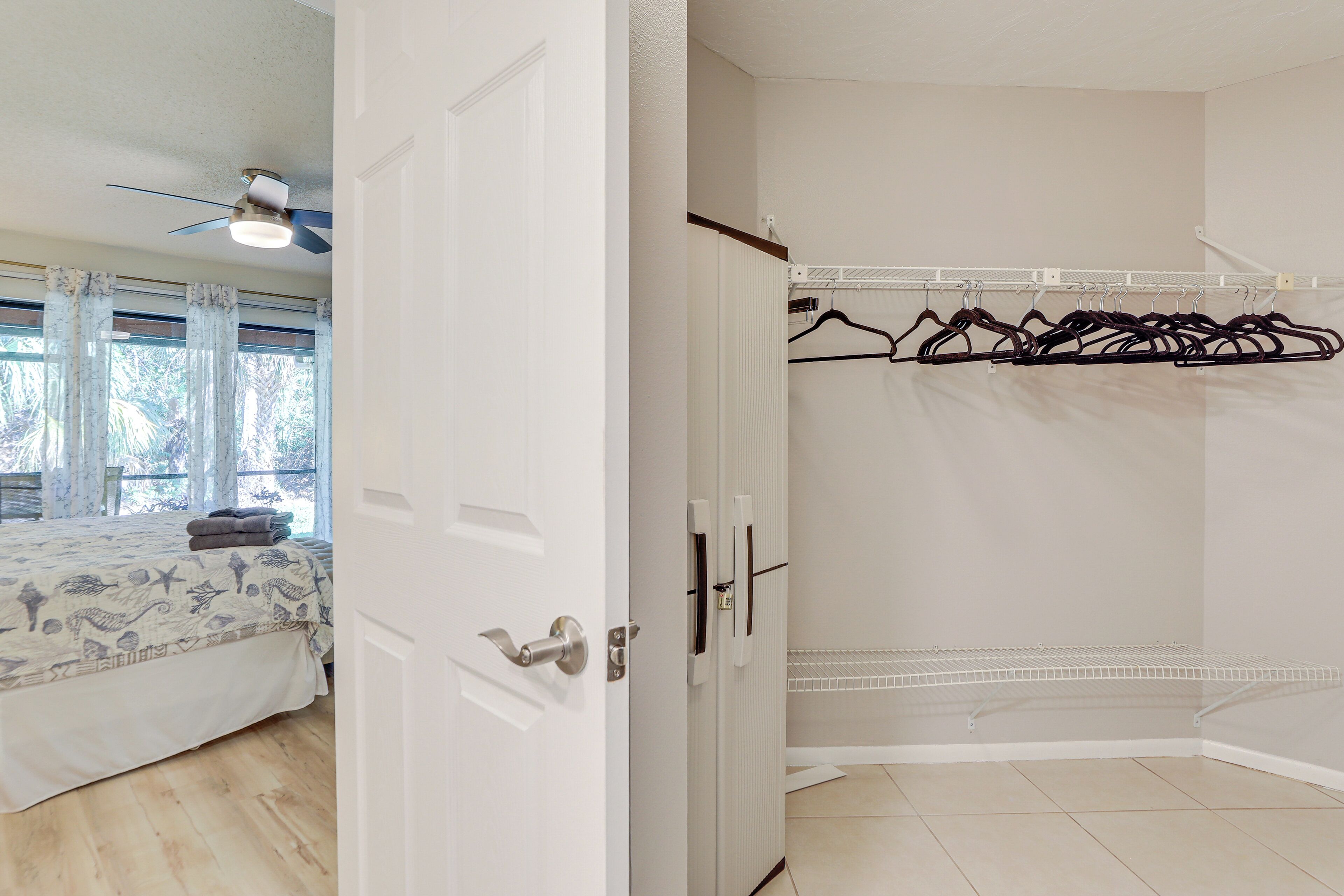 A bedroom with a bed, a ceiling fan, and a window with curtains.