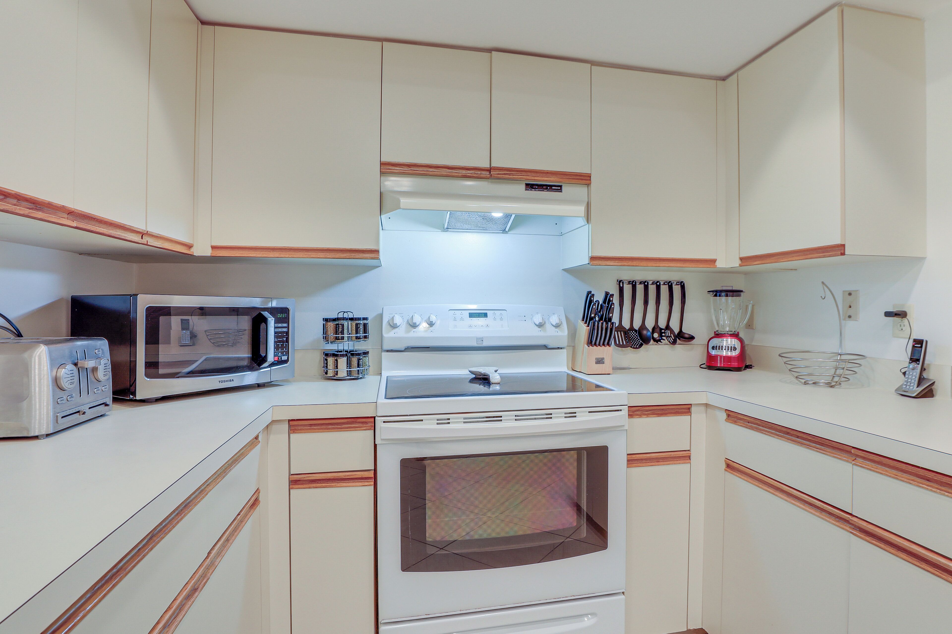 A kitchen with a microwave, toaster, stove, and oven.