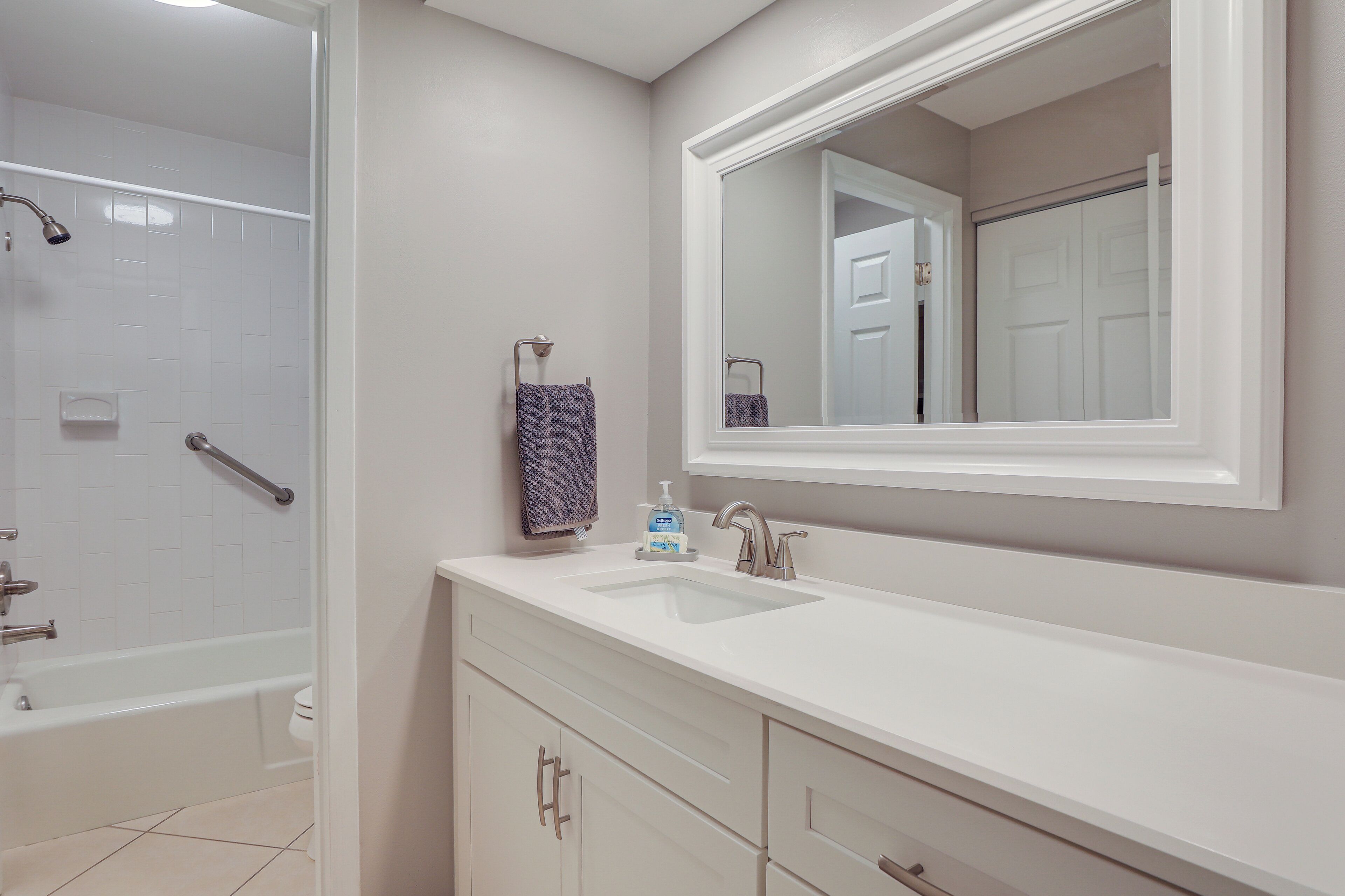 A bathroom with a bathtub, a sink, and a mirror.
