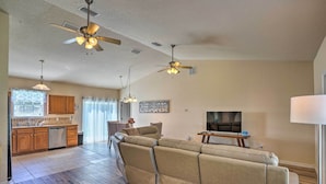 A spacious living room with a large beige sectional sofa, a dining area with wooden cabinets, and a kitchen with a dishwasher. - Sebring Gem: Close to Golf & Raceway (Sebring)