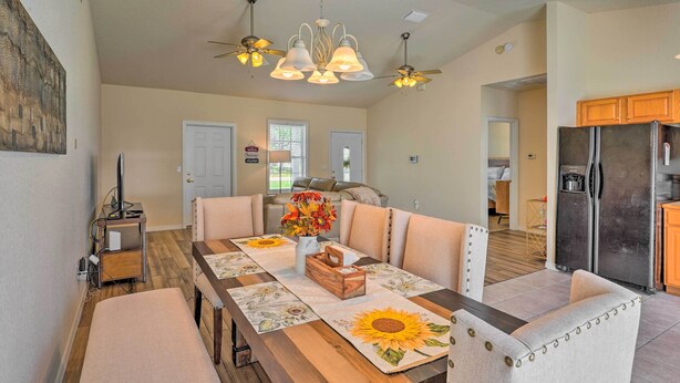 A dining area with a long wooden table, cushioned chairs, and a chandelier. - Sebring Gem: Close to Golf & Raceway (Sebring)