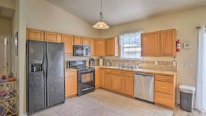 A kitchen with wooden cabinets, a black refrigerator, a microwave, a stove, and a dishwasher. - Sebring Gem: Close to Golf & Raceway (Sebring)