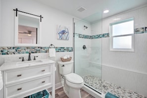 A bathroom with a white vanity, a glass shower enclosure, and a tiled backsplash. - Riverfront Home w/ Putting Green & Boat Dock! (New Port Richey)