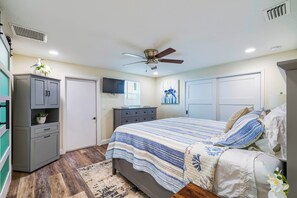 A bedroom with a bed, dresser, ceiling fan, and a television on the wall. - Riverfront Home w/ Putting Green & Boat Dock! (New Port Richey)