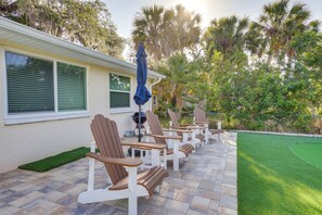 A patio with outdoor seating, a barbecue grill, and a well-maintained lawn.
