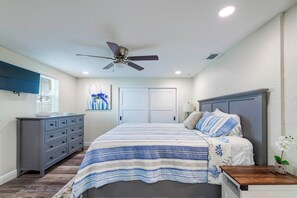 Une chambre à coucher avec un lit, une commode, un ventilateur de plafond et une fenêtre.