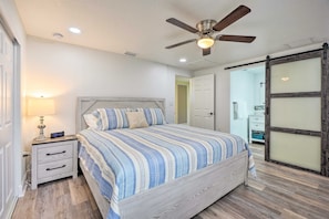 A bedroom with a bed, nightstand, lamp, ceiling fan, and a sliding door. - Riverfront Home w/ Putting Green & Boat Dock! (New Port Richey)
