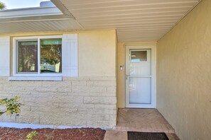 A house with a white exterior, a front door, and a small front porch with a brick floor.