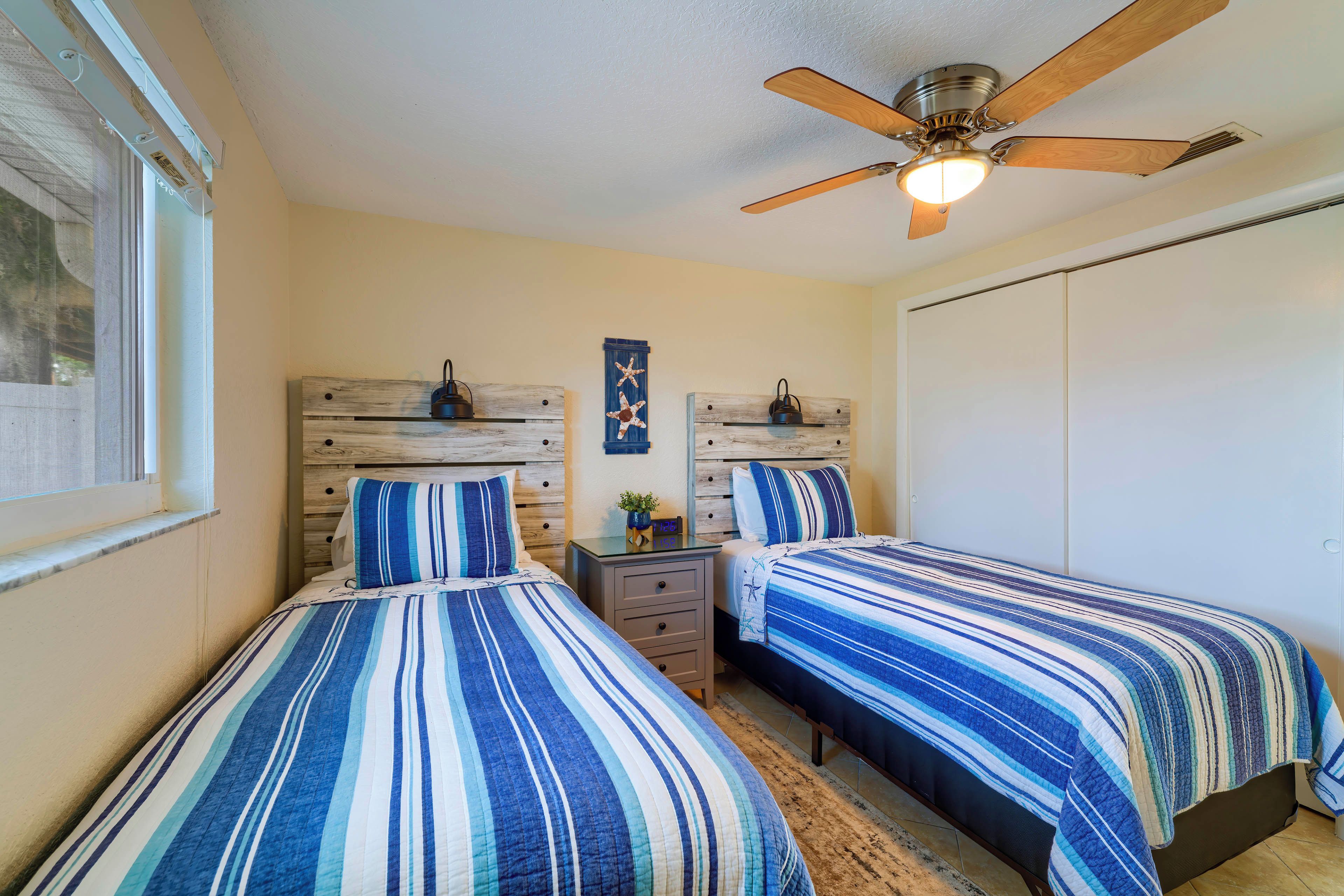 A bedroom with two beds, a ceiling fan, and a wardrobe.