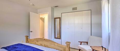 A bedroom with a bed, a wooden headboard, a ceiling fan, a chair, and a wardrobe.